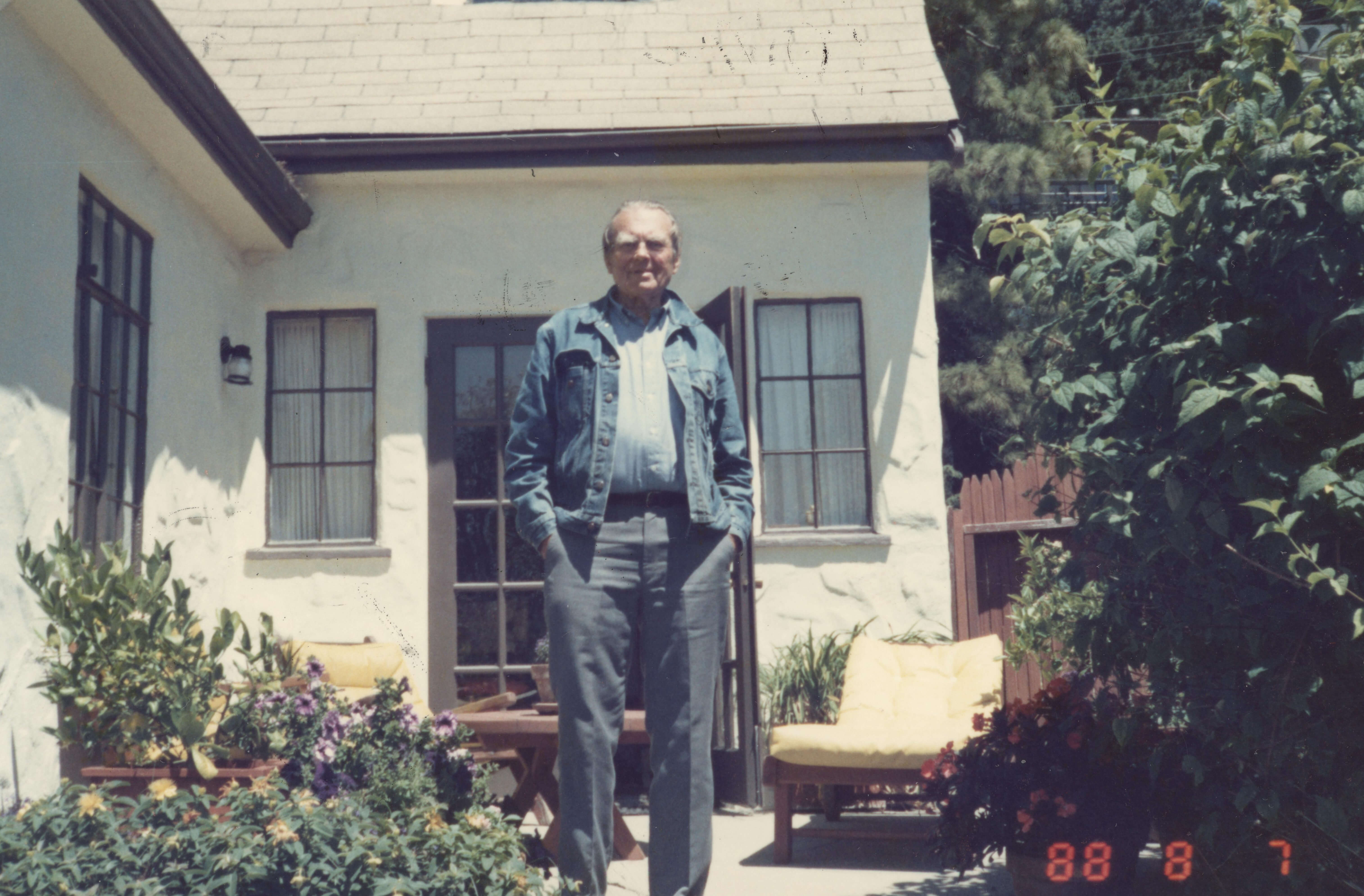 Poeta Czesław Miłosz w słoneczny dzień stoi przed domem w Berkley, 7 lipca 1988 roku